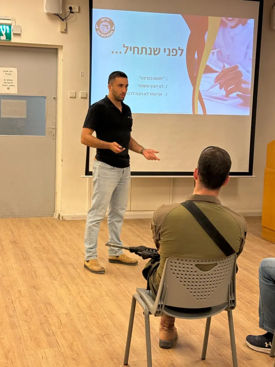 עו״ד אופק ברנע מעביר הרצאה מול משתתפים, אחד מהם עם נשק